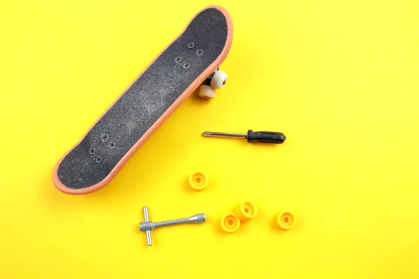 黄色の背景にツールとミニ スケート ボード グッズ — ストック写真