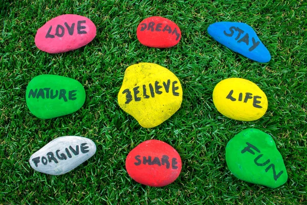 Yeşil çimenlerin üzerinde kelimelerle renkli taş
