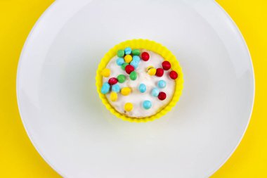 Sarı zemin üzerine vanilya buzlu Cupcake