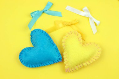 Sarı zemin üzerine sarı ve mavi keçe kalp ve kurdeleler Üstten Görünüm 