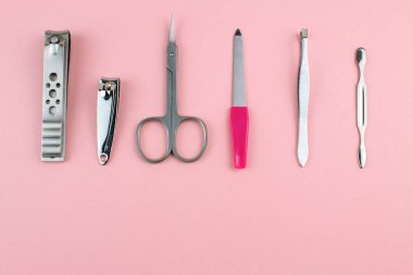 Manikür ve pedikür araçları pembe bir arka plan üzerinde