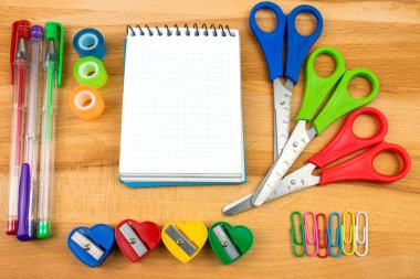 Ahşap masa üstünde renkli okul kırtasiyesinin yakın plan fotoğrafı.