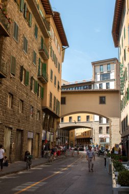 Florence, İtalya - önce 25 2017: Ponte Vecchio yakınındaki bir Floransa sokakta yürüyen turist. Arka plan Vasari Corridor.The Vasari Koridor Floransa'daki Pitti Palace ile Palazzo Vecchio bağlayan yükseltilmiş bir teras olmasıdır.