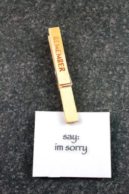 top view of wooden Remember clothespin with say im sorry note on dark background  clipart