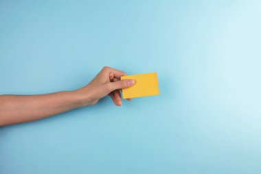 Mavi arka planda altın kart tutan bir kadının kırpılmış fotoğrafı.