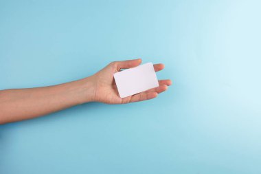 Mavi zemin üzerinde boş bir kart tutan bir kadının kırpılmış fotoğrafı.