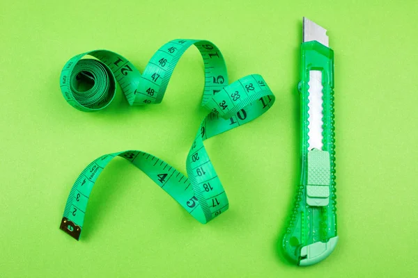 グリーン プラスチック カッター 測定用紙の背景にテープ — ストック写真