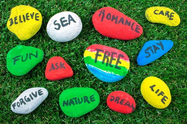 Yeşil çimenlerin üzerinde kelimelerle renkli taş