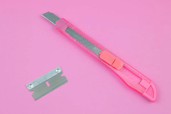 Pink Plastic Cutter and blade on Paper background