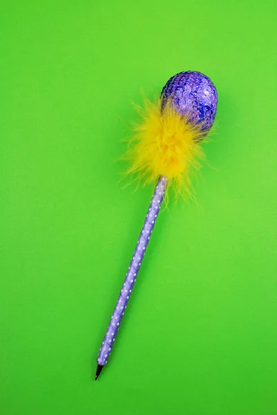 紫色亮片复活节彩蛋与羽毛在笔在绿色背景 — 图库照片