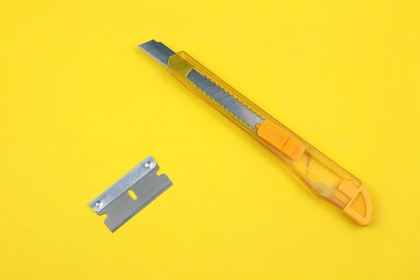 Yellow Plastic Cutter and blade on Paper background
