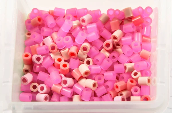 close-up shot of pink plastic beads in box on white