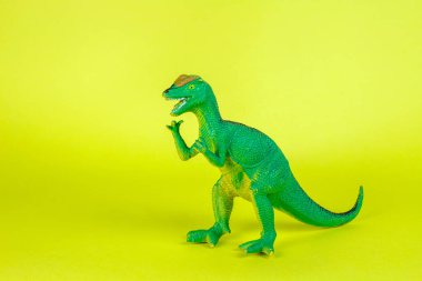 Dinozor plastik oyuncak sarı arka planda.