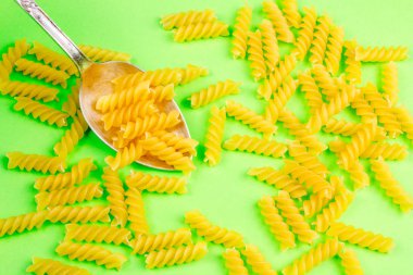 Yeşil zemin üzerine gümüş kaşık makarna.