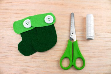 close-up shot of decorative green boots with sewing supplies on wooden table