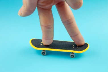 Mavi arka plan üzerinde Mini kaykay oyuncakla oynamak adam