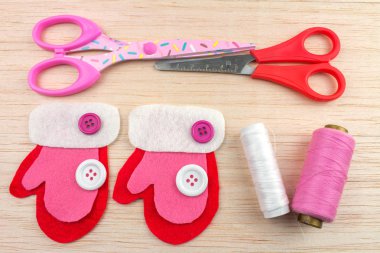 Eldivenler, konu düğmeleri ve makaslar ahşap masa olan pembe dekoratif Noel hissettim 