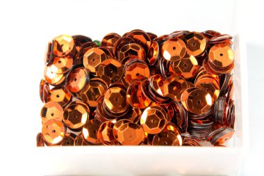 close-up shot of orange sequins in box on tabletop