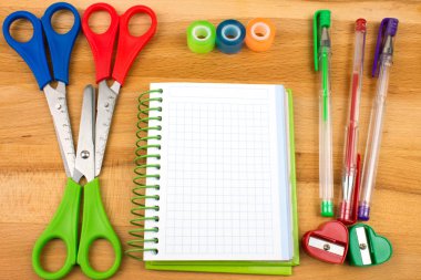 Ahşap masa üstünde renkli okul kırtasiyesinin yakın plan fotoğrafı.