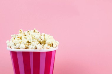 Pembe bir arka plan üzerinde pembe çizgili Kova patlamış mısır