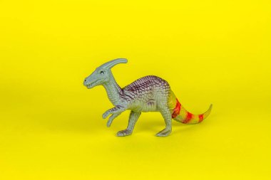 Dinozor plastik oyuncak sarı arka planda.