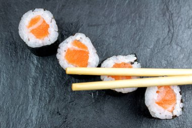 Üstten Görünüm suşi ile Somon siyah taş masaya çubuklarla rulo