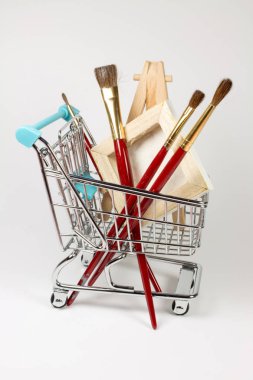 Beyaz yüzeydeki boya malzemeleriyle alışveriş arabasının yakın çekim görüntüsü.