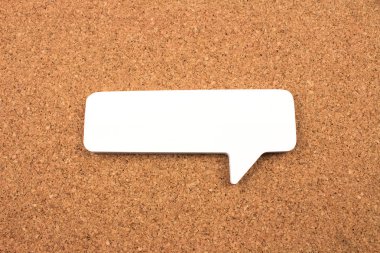 close-up shot of blank paper speech bubble on cork background