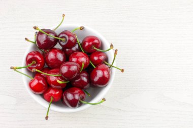 Beyaz ahşap arka plan üzerinde kase kırmızı tatlı kiraz