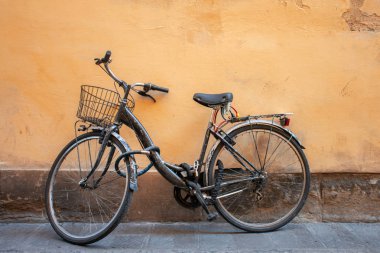 Beton duvarın yanında paslı eski bir bisiklet.