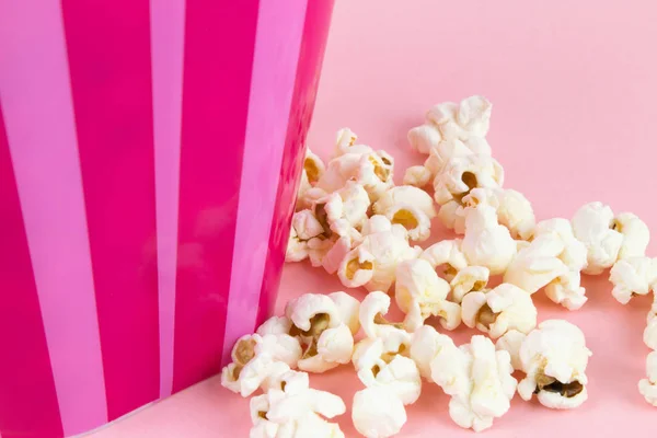 Pembe bir arka plan üzerinde pembe çizgili Kova patlamış mısır