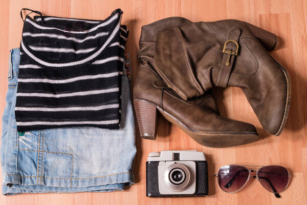 top view shot of stylish female clothes with vintage camera on wooden table