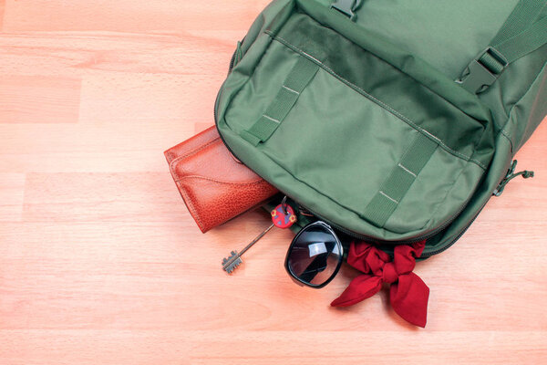 close-up shot of backpack with stylish accessories on wooden surface