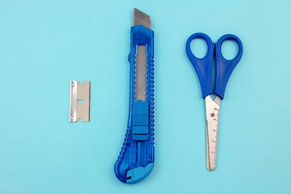 Blue Plastic Cutter, blade and scissors on Paper background