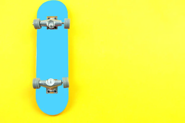 黄色の背景に青のミニ スケート ボード グッズ — ストック写真
