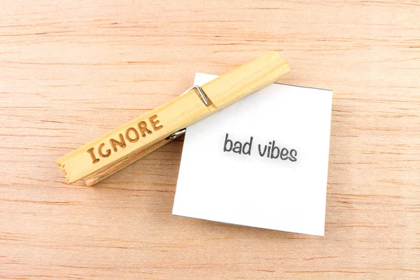 top view of ignore clothespin with bad vibes note on wooden background