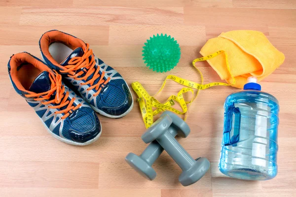 sport equipment, bottle, shoes and measuring tape on wooden background