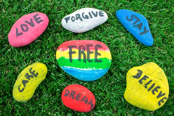 Yeşil çimenlerin üzerinde kelimelerle renkli taş