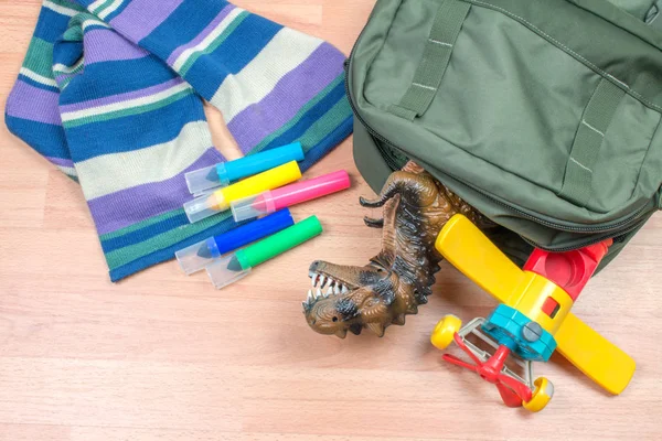 close-up shot of backpack with toys lying on wooden floor