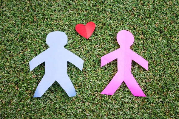 paper couple with heart sign on green grass background