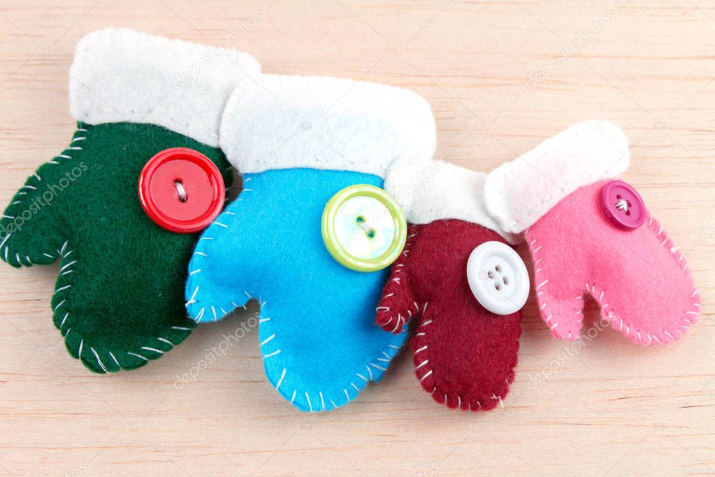 colorful decorative christmas felt gloves with buttons on wooden table 