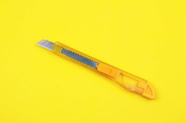 Kağıt arka plan üzerinde sarı plastik kesici
