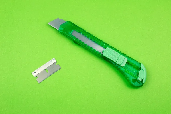 Green Plastic Cutter and blade on Paper background