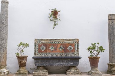 Kenarlarında dekoratif fayanslar olan duvar tezgahı beyaz arka planda iki saksı, Cordoba terası, ahenkli kompozisyon
