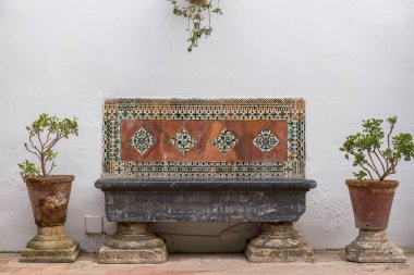 Kenarlarında dekoratif fayanslar olan duvar tezgahı beyaz arka planda iki saksı, Cordoba terası, ahenkli kompozisyon