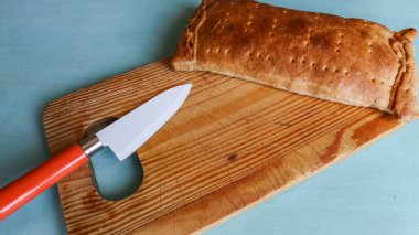 Açık mavi yüzeyde, tahta tahtada bıçaklı turta.