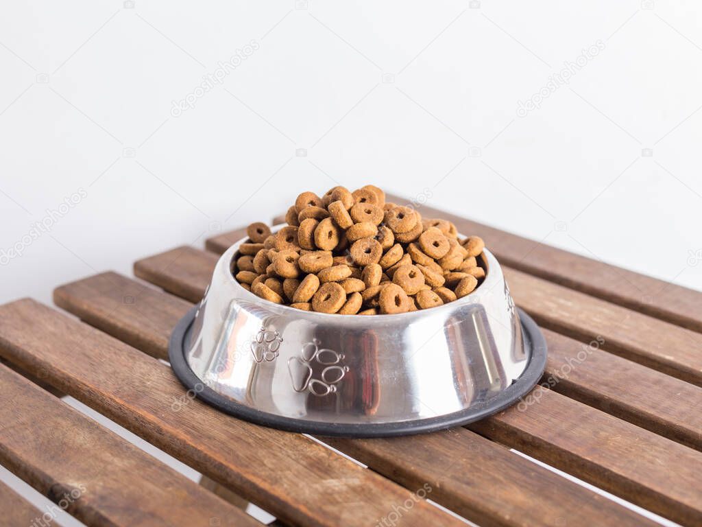 silver bowl full of dog food on a wooden table and white background