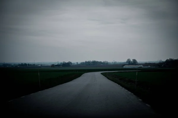 A rural road across the farmlands on a dark and gloomy winter day in southern Sweden