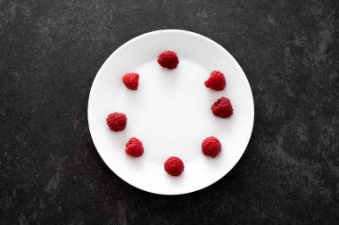 Yuvarlak desenli ahududu manzarası beyaz bir plaka üzerinde koyu taştan bir masa ve fotokopi alanı.