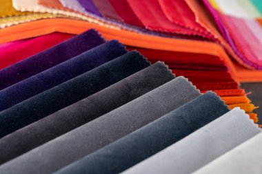 Rengarenk renkli kadife numuneler sırayla katlandı ve bir masanın üzerine yığıldı.